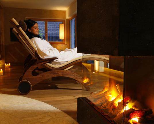 A woman relaxes at the fireplace in the relaxation room